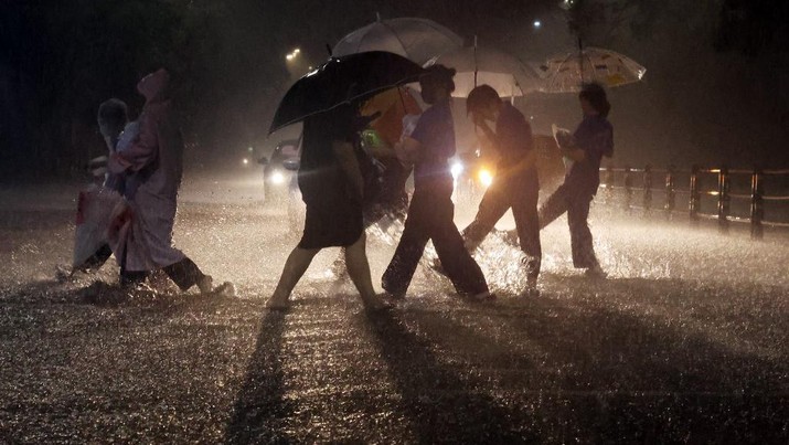 Orang-orang berjalan melintasi jalan saat hujan deras di distrik Gangbuk Seoul, Korea Selatan, Senin (8/8/2022). (Photo by YONHAP / AFP)