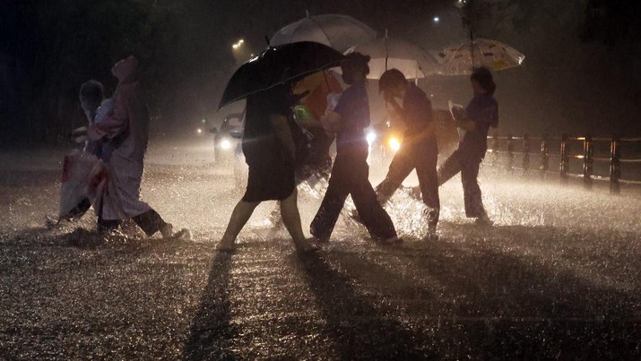 Banjir di Seoul Korea Selatan Orang-orang berjalan melintasi jalan saat hujan deras di distrik Gangbuk Seoul, Korea Selatan, Senin (8/8/2022). (Photo by YONHAP / AFP)