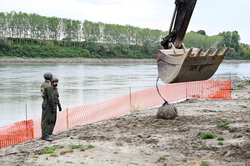 Anggota tentara Italis mengeluarkan bom Perang Dunia Kedua yang ditemukan di Sungai Po yang mengering di Borgo Virgilio, Italia, Minggu (7/8/2022). (REUTERS/Flavio Lo Scalzo)
