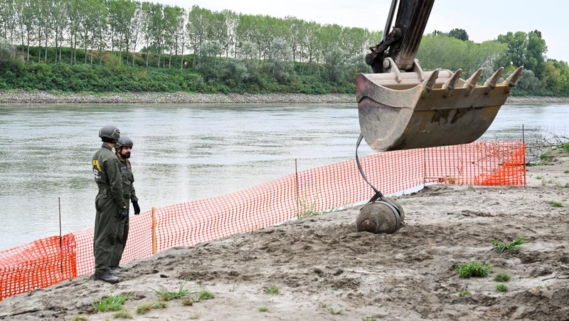 Anggota tentara Italis mengeluarkan bom Perang Dunia Kedua yang ditemukan di Sungai Po yang mengering di Borgo Virgilio, Italia, Minggu (7/8/2022). (REUTERS/Flavio Lo Scalzo)