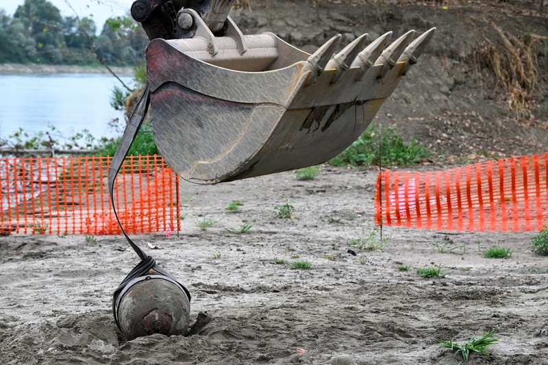 Anggota tentara Italis mengeluarkan bom Perang Dunia Kedua yang ditemukan di Sungai Po yang mengering di Borgo Virgilio, Italia, Minggu (7/8/2022). (REUTERS/Flavio Lo Scalzo)