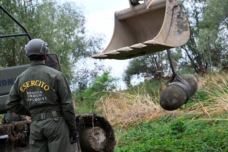 Anggota tentara Italis mengeluarkan bom Perang Dunia Kedua yang ditemukan di Sungai Po yang mengering di Borgo Virgilio, Italia, Minggu (7/8/2022). (REUTERS/Flavio Lo Scalzo)