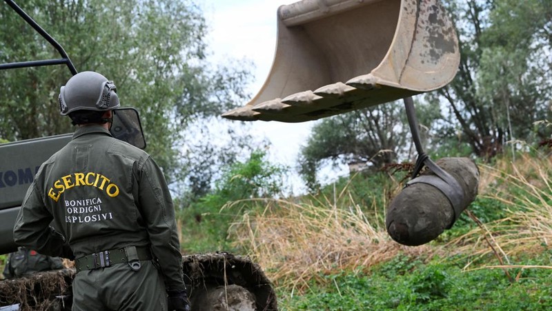 Anggota tentara Italis mengeluarkan bom Perang Dunia Kedua yang ditemukan di Sungai Po yang mengering di Borgo Virgilio, Italia, Minggu (7/8/2022). (REUTERS/Flavio Lo Scalzo)