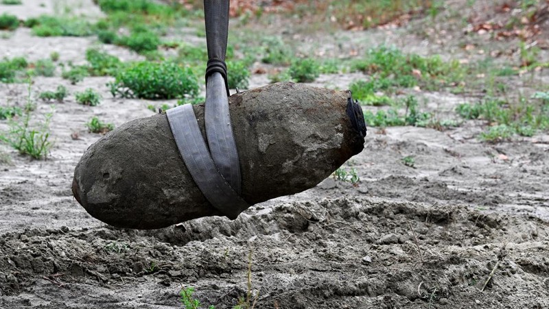 Anggota tentara Italis mengeluarkan bom Perang Dunia Kedua yang ditemukan di Sungai Po yang mengering di Borgo Virgilio, Italia, Minggu (7/8/2022). (REUTERS/Flavio Lo Scalzo)