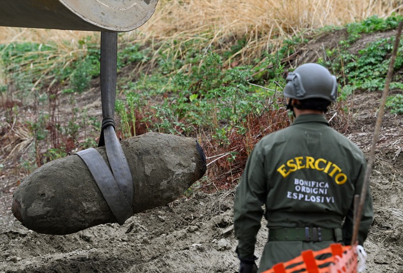 Anggota tentara Italis mengeluarkan bom Perang Dunia Kedua yang ditemukan di Sungai Po yang mengering di Borgo Virgilio, Italia, Minggu (7/8/2022). (REUTERS/Flavio Lo Scalzo)
