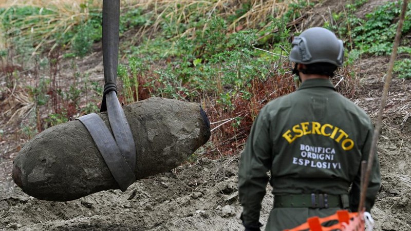 Anggota tentara Italis mengeluarkan bom Perang Dunia Kedua yang ditemukan di Sungai Po yang mengering di Borgo Virgilio, Italia, Minggu (7/8/2022). (REUTERS/Flavio Lo Scalzo)