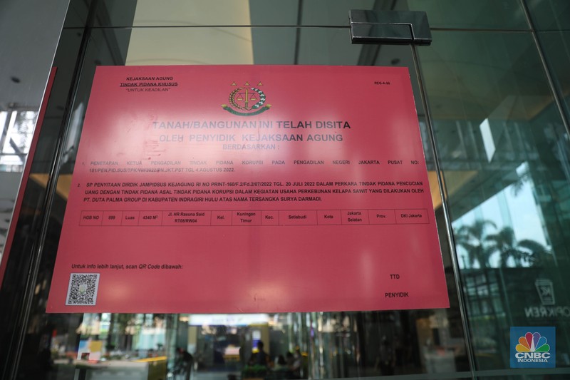 Penyitaan aset Surya Darmadi di Gedung Palma One Pekerja melintas di depan papan bertuliskan sitaan aset Surya Darmadi di Gedung Palma One, Jakarta, Selasa (9/8/2022). Kejaksaan Agung telah menyita sebanyak 23 aset milik PT Duta Palma Group terkait tersangka kasus korupsi Rp 78 triliun, Surya Darmadi. (CNBC Indonesia/ Muhammad Sabki)