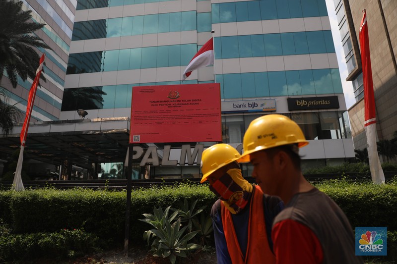 Penyitaan aset Surya Darmadi di Gedung Palma One Pekerja melintas di depan papan bertuliskan sitaan aset Surya Darmadi di Gedung Palma One, Jakarta, Selasa (9/8/2022). Kejaksaan Agung telah menyita sebanyak 23 aset milik PT Duta Palma Group terkait tersangka kasus korupsi Rp 78 triliun, Surya Darmadi. (CNBC Indonesia/ Muhammad Sabki)