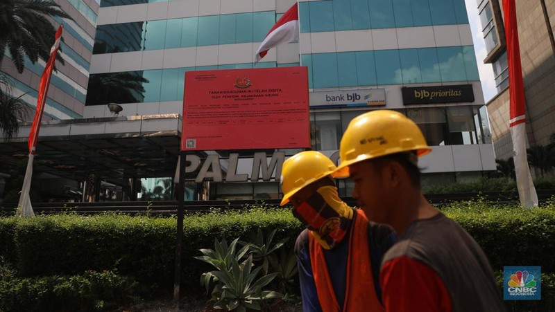Pekerja melintas di depan papan bertuliskan sitaan aset Surya Darmadi di Gedung Palma One, Jakarta, Selasa (9/8/2022). Kejaksaan Agung telah menyita sebanyak 23 aset milik PT Duta Palma Group terkait tersangka kasus korupsi Rp 78 triliun, Surya Darmadi. (CNBC Indonesia/ Muhammad Sabki)