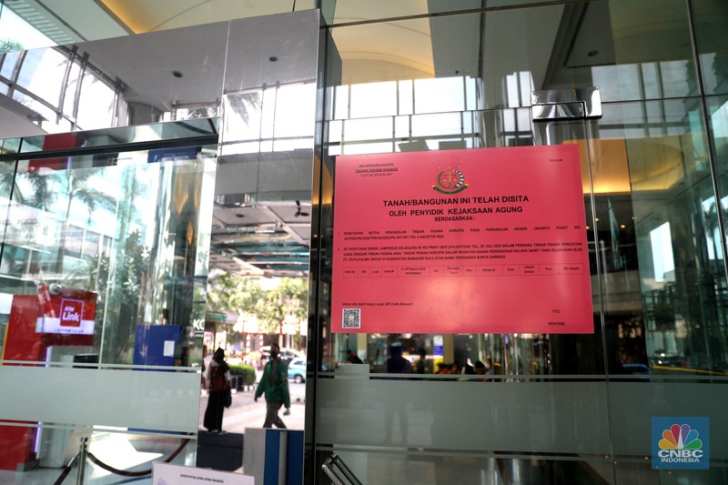 Penyitaan aset Surya Darmadi di Gedung Palma One Pekerja melintas di depan papan bertuliskan sitaan aset Surya Darmadi di Gedung Palma One, Jakarta, Selasa (9/8/2022). Kejaksaan Agung telah menyita sebanyak 23 aset milik PT Duta Palma Group terkait tersangka kasus korupsi Rp 78 triliun, Surya Darmadi. (CNBC Indonesia/ Muhammad Sabki)