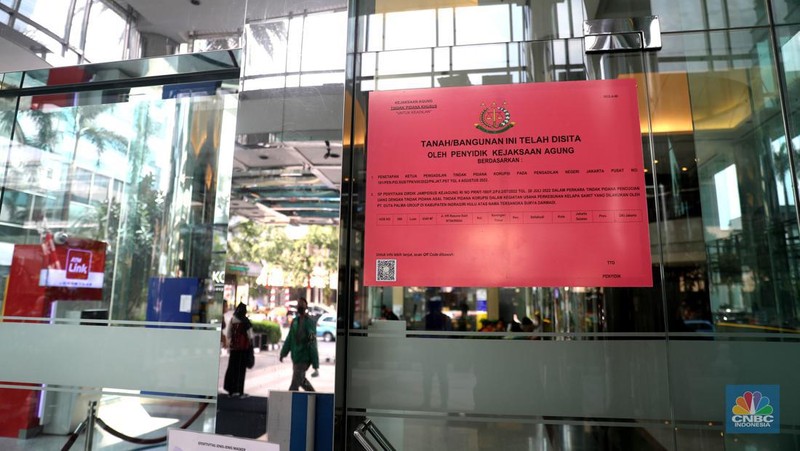 Pekerja melintas di depan papan bertuliskan sitaan aset Surya Darmadi di Gedung Palma One, Jakarta, Selasa (9/8/2022). Kejaksaan Agung telah menyita sebanyak 23 aset milik PT Duta Palma Group terkait tersangka kasus korupsi Rp 78 triliun, Surya Darmadi. (CNBC Indonesia/ Muhammad Sabki)