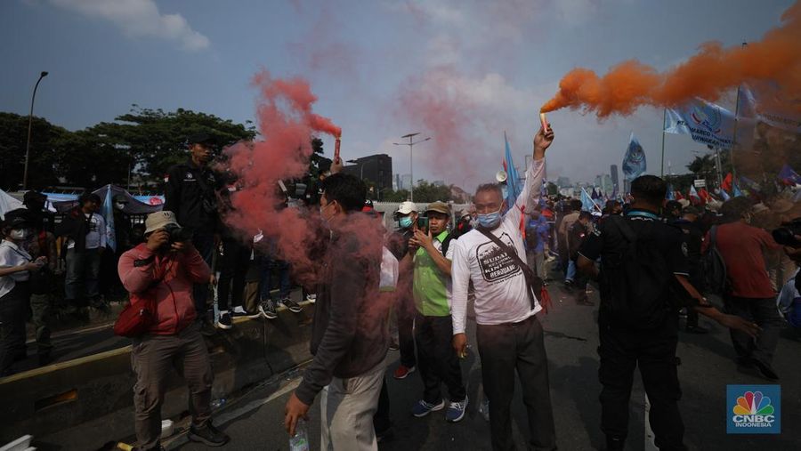 Sejumlah massa buruh melakukan aski di depan gedung DPR/MPR, Jakarta, Rabu (10/8/022). Dalam aksinya mereka mengibarkan bendera serta membentangkan atribut seperti poster dan spanduk bertulisan tuntutan pencabutan Undang-Undang Cipta Kerja. (CNBC Indonesia/ Tri Susilo)