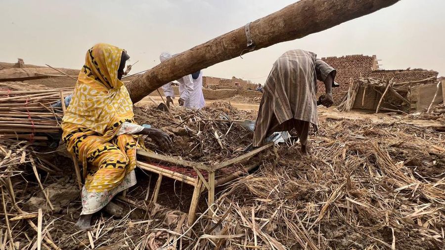 Warga beraktivitas usai banjir akibat hujan lebat yang melanda pemukiman mereka di Sudan, Sabtu (13/8/2022). Akibat banjir tersebut banyak rumah rusak dan menyebabkan korban tewas. (Photo by Sami Alopap/Anadolu Agency via Getty Images)