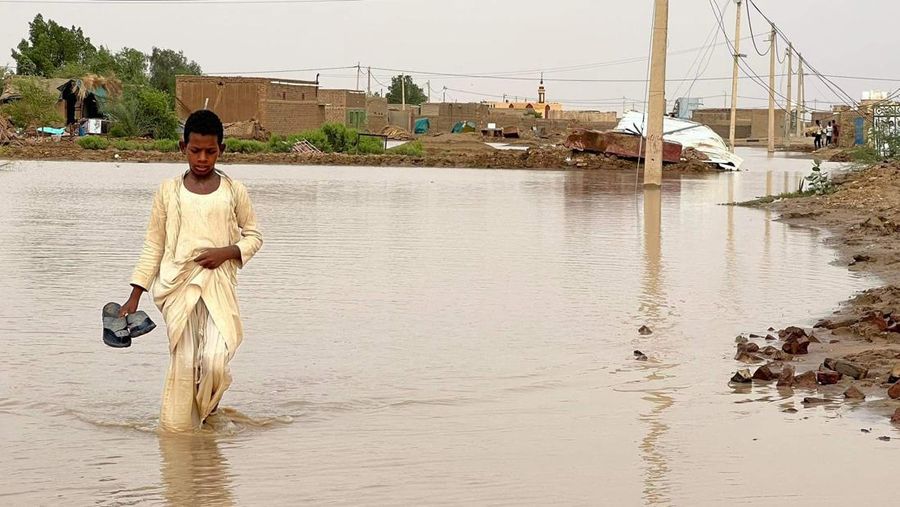Warga beraktivitas usai banjir akibat hujan lebat yang melanda pemukiman mereka di Sudan, Sabtu (13/8/2022). Akibat banjir tersebut banyak rumah rusak dan menyebabkan korban tewas. (Photo by Sami Alopap/Anadolu Agency via Getty Images)