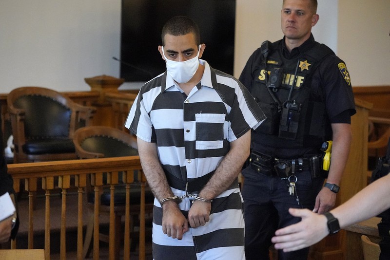 Hadi Matar (24) tengah, tiba untuk dakwaan di Gedung Pengadilan Chautauqua County di Mayville, NY, Sabtu (13/8/2022).. Matar, yang dituduh melakukan serangan penikaman terhadap penulis “Satanic Verses” Salman Rushdie telah masuk pembelaan tidak bersalah di pengadilan New York atas tuduhan percobaan pembunuhan dan penyerangan. (AP Photo/Gene J. Puskar)