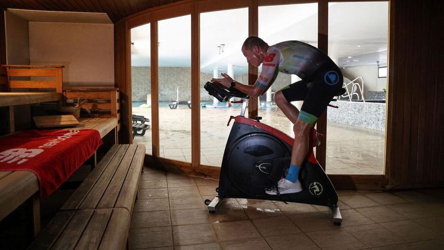 French triathlete Ludovic Chorgnon trains on an exercise bike in a sauna in La Possesion, on the French Indian Ocean island of La Reunion, on June 17, 2022. - Chorgnon, 50, is training for the 