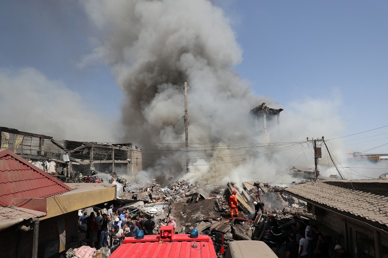 Petugas pemadam kebakaran memadamkan api setelah terjadi ledakan pada gudang kembang api di sebuah pusat perbelanjaan di Yerevan, Armenia, MInggu (14/8/2022). (Vahram Baghdasaryan/Photolure via REUTERS)