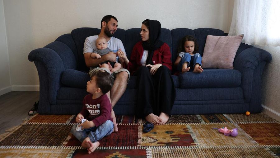 Keluarga Mohammadi, Najib menggendong Yusuf, Yasar, Susan dan Zahra, duduk bersama di ruang tamu mereka, di rumah mereka di Sacramento, California, AS, Senin (1/8/2022). Najib Mohammadi memiliki harapan besar untuk hidupnya di Amerika Serikat ketika dia , istrinya yang sedang hamil Susan dan dua anaknya yang masih kecil meninggalkan Afghanistan pada Juli 2021. (REUTERS/Brittany Hosea-Small)