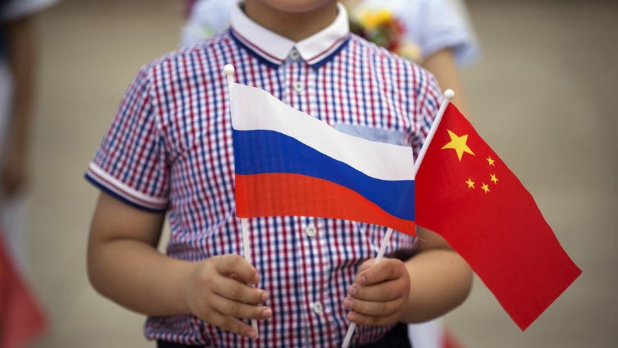 A boy holds Russian, left, and Chinese flags before a welcoming ceremony for Russian President Vladimir Putin at the Great Hall of the People in Beijing, Saturday, June 25, 2016. (AP Photo/Mark Schiefelbein)