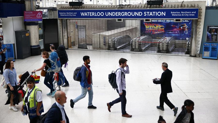 Demo Pekerja Kereta Bawah Tanah di Waterloo, London, Inggris, Orang-orang berjalan melewati gerbang tertutup saat stasiun bawah tanah Waterloo tak beroperasi di London, Inggris, Jumat (19/8/2022). Kereta bawah tanah ditutup akibat ribuan pekerja kereta api di Inggris kembali menggelar aksi mogok yang merupakan buntut dari perselisihan yang sedang berlangsung mengenai gaji dan kondisi kerja yang diperburuk oleh krisis biaya hidup yang semakin dalam. (REUTERS/Henry Nicholls)
