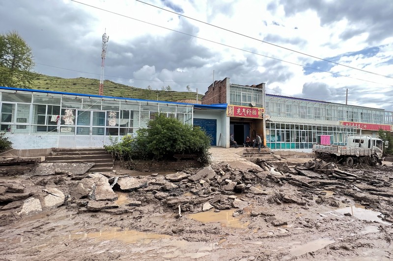 Seorang pekerja penyelamat dan anjing mencari korban setelah banjir di Desa Shadai, Kotapraja Qingshan di Datong Hui dan Kabupaten Otonom Tu di Provinsi Qinghai, Tiongkok barat laut, Kamis (18/8/2022). Badai hujan yang melanda Tiongkok barat memicu tanah longsor yang mengalihkan sungai dan menyebabkan banjir bandang di daerah berpenduduk, menewaskan beberapa orang dan membuat yang lain hilang.  (Zhang Hongxiang/Xinhua via AP)