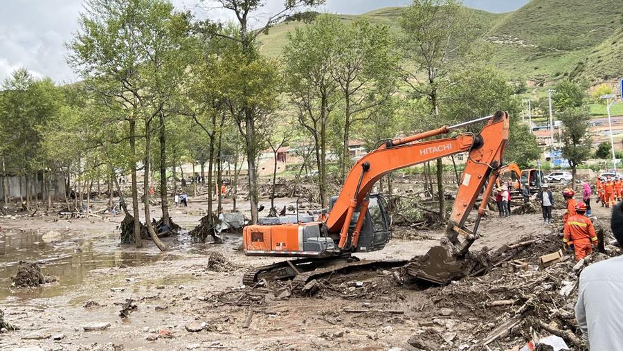 Seorang pekerja penyelamat dan anjing mencari korban setelah banjir di Desa Shadai, Kotapraja Qingshan di Datong Hui dan Kabupaten Otonom Tu di Provinsi Qinghai, Tiongkok barat laut, Kamis (18/8/2022). Badai hujan yang melanda Tiongkok barat memicu tanah longsor yang mengalihkan sungai dan menyebabkan banjir bandang di daerah berpenduduk, menewaskan beberapa orang dan membuat yang lain hilang.  (Zhang Hongxiang/Xinhua via AP)