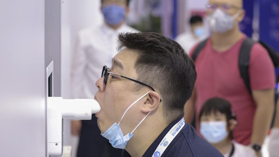 BEIJING, CHINA - AUGUST 18: A staff member takes part in a demonstration of a robot arm collecting swab samples for coronavirus disease (COVID-19) detection during the 2022 World Robot Conference at Beijing Etrong International Exhibition on August 18, 2022 in Beijing, China. The 2022 World Robot Conference kicked off on Thursday in Beijing. (Photo by Lintao Zhang/Getty Images)