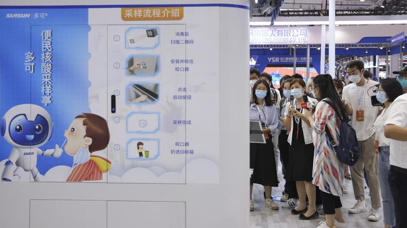 BEIJING, CHINA - AUGUST 18: A staff member takes part in a demonstration of a robot arm collecting swab samples for coronavirus disease (COVID-19) detection during the 2022 World Robot Conference at Beijing Etrong International Exhibition on August 18, 2022 in Beijing, China. The 2022 World Robot Conference kicked off on Thursday in Beijing. (Photo by Lintao Zhang/Getty Images)