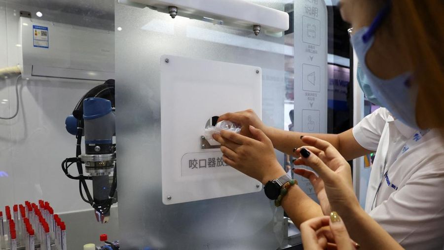 BEIJING, CHINA - AUGUST 18: A staff member takes part in a demonstration of a robot arm collecting swab samples for coronavirus disease (COVID-19) detection during the 2022 World Robot Conference at Beijing Etrong International Exhibition on August 18, 2022 in Beijing, China. The 2022 World Robot Conference kicked off on Thursday in Beijing. (Photo by Lintao Zhang/Getty Images)