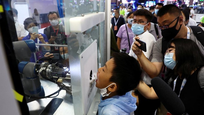 BEIJING, CHINA - AUGUST 18: A staff member takes part in a demonstration of a robot arm collecting swab samples for coronavirus disease (COVID-19) detection during the 2022 World Robot Conference at Beijing Etrong International Exhibition on August 18, 2022 in Beijing, China. The 2022 World Robot Conference kicked off on Thursday in Beijing. (Photo by Lintao Zhang/Getty Images)