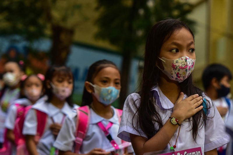A teacher uses hand sanitizer on a student on the first day of in-person classes after years-long Covid-19 lockdowns at Pedro Guevara Elementary School in Manila on August 22, 2022. (Photo by Maria Tan / AFP) (Photo by MARIA TAN/AFP via Getty Images)