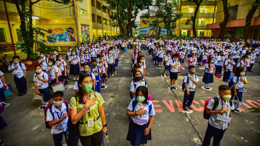 A teacher uses hand sanitizer on a student on the first day of in-person classes after years-long Covid-19 lockdowns at Pedro Guevara Elementary School in Manila on August 22, 2022. (Photo by Maria Tan / AFP) (Photo by MARIA TAN/AFP via Getty Images)
