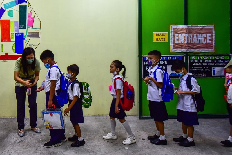 A teacher uses hand sanitizer on a student on the first day of in-person classes after years-long Covid-19 lockdowns at Pedro Guevara Elementary School in Manila on August 22, 2022. (Photo by Maria Tan / AFP) (Photo by MARIA TAN/AFP via Getty Images)