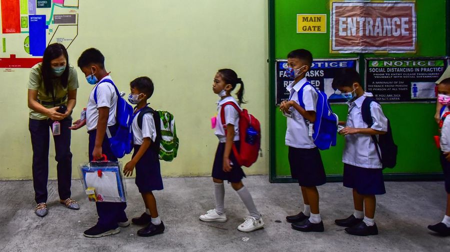 A teacher uses hand sanitizer on a student on the first day of in-person classes after years-long Covid-19 lockdowns at Pedro Guevara Elementary School in Manila on August 22, 2022. (Photo by Maria Tan / AFP) (Photo by MARIA TAN/AFP via Getty Images)