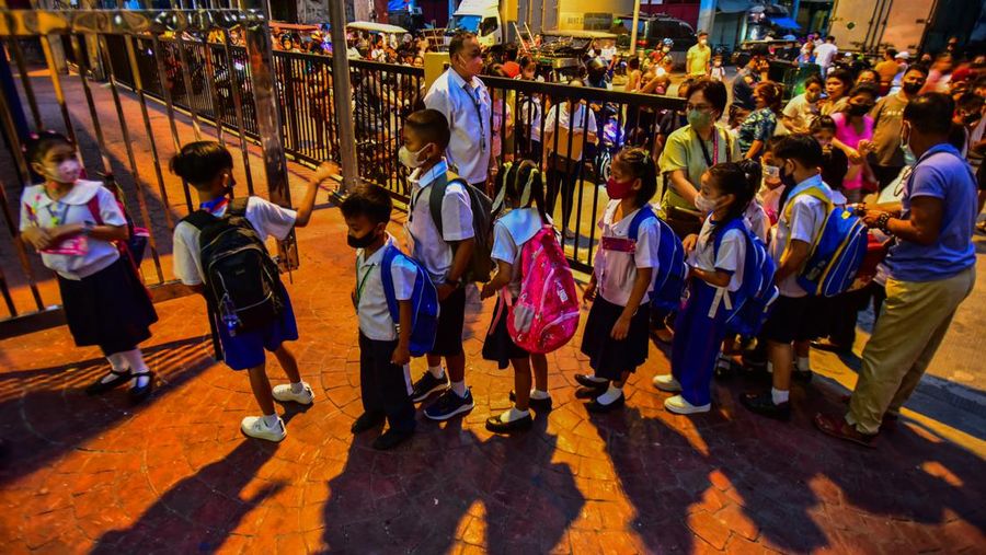 A teacher uses hand sanitizer on a student on the first day of in-person classes after years-long Covid-19 lockdowns at Pedro Guevara Elementary School in Manila on August 22, 2022. (Photo by Maria Tan / AFP) (Photo by MARIA TAN/AFP via Getty Images)