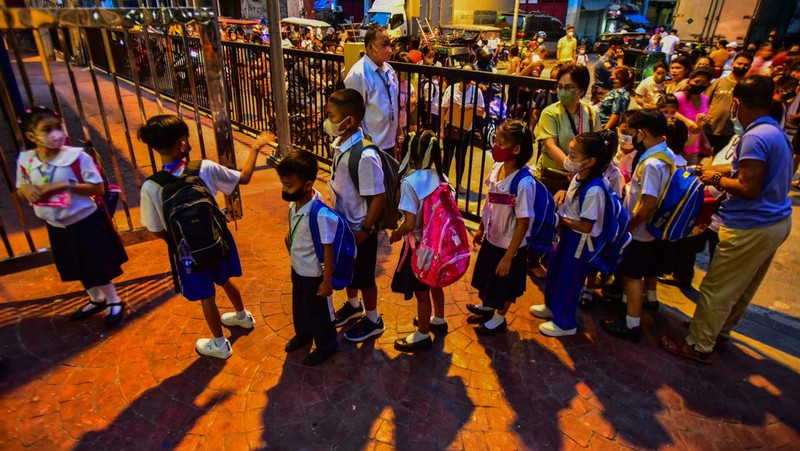 A teacher uses hand sanitizer on a student on the first day of in-person classes after years-long Covid-19 lockdowns at Pedro Guevara Elementary School in Manila on August 22, 2022. (Photo by Maria Tan / AFP) (Photo by MARIA TAN/AFP via Getty Images)