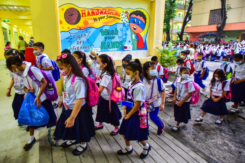A teacher uses hand sanitizer on a student on the first day of in-person classes after years-long Covid-19 lockdowns at Pedro Guevara Elementary School in Manila on August 22, 2022. (Photo by Maria Tan / AFP) (Photo by MARIA TAN/AFP via Getty Images)