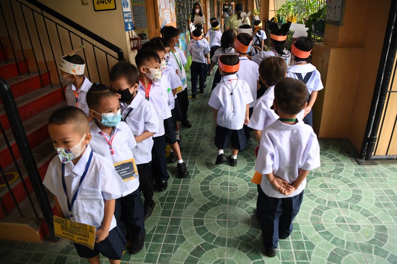 A teacher uses hand sanitizer on a student on the first day of in-person classes after years-long Covid-19 lockdowns at Pedro Guevara Elementary School in Manila on August 22, 2022. (Photo by Maria Tan / AFP) (Photo by MARIA TAN/AFP via Getty Images)