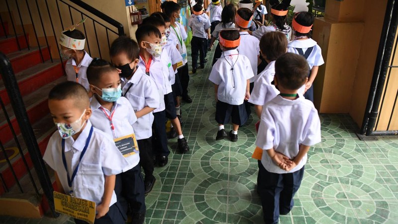 A teacher uses hand sanitizer on a student on the first day of in-person classes after years-long Covid-19 lockdowns at Pedro Guevara Elementary School in Manila on August 22, 2022. (Photo by Maria Tan / AFP) (Photo by MARIA TAN/AFP via Getty Images)