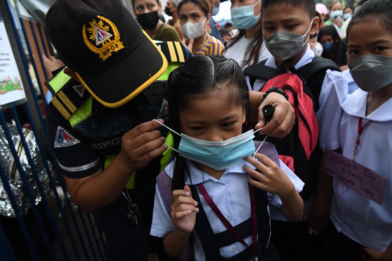 A teacher uses hand sanitizer on a student on the first day of in-person classes after years-long Covid-19 lockdowns at Pedro Guevara Elementary School in Manila on August 22, 2022. (Photo by Maria Tan / AFP) (Photo by MARIA TAN/AFP via Getty Images)