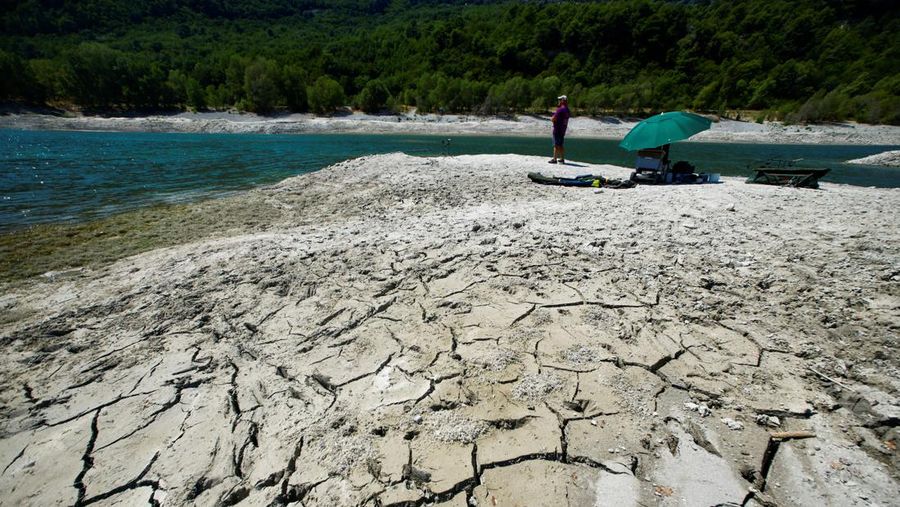 A fisherman is seen on cracked and dry earth of the banks of Le Broc lake, as a historical drought hits France, August 5, 2022. REUTERS/Eric Gaillard