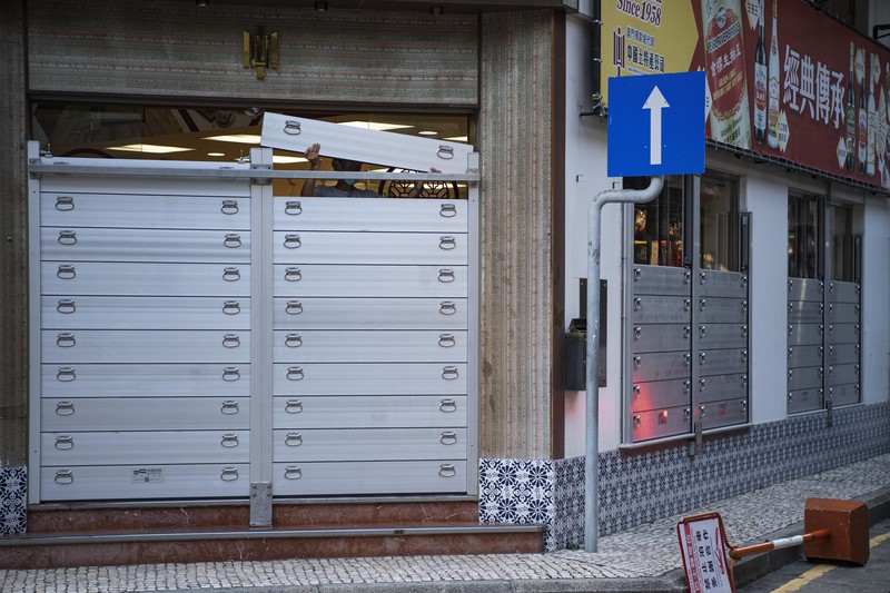 In this photo released by Xinhua News Agency, a worker installs a waterproof gate at a store in Macao, China, Thursday, Aug. 24, 2022. A tropical storm was forecast to make landfall in southern China later Thursday after bringing rain and stiff winds to Hong Kong overnight as it passed to the south of the Asian financial center. (Cheong Kam Ka/Xinhua via AP)