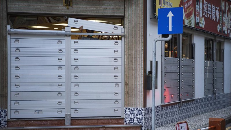 In this photo released by Xinhua News Agency, a worker installs a waterproof gate at a store in Macao, China, Thursday, Aug. 24, 2022. A tropical storm was forecast to make landfall in southern China later Thursday after bringing rain and stiff winds to Hong Kong overnight as it passed to the south of the Asian financial center. (Cheong Kam Ka/Xinhua via AP)