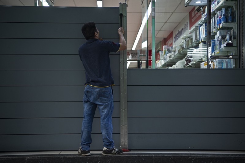 In this photo released by Xinhua News Agency, a worker installs a waterproof gate at a store in Macao, China, Thursday, Aug. 24, 2022. A tropical storm was forecast to make landfall in southern China later Thursday after bringing rain and stiff winds to Hong Kong overnight as it passed to the south of the Asian financial center. (Cheong Kam Ka/Xinhua via AP)