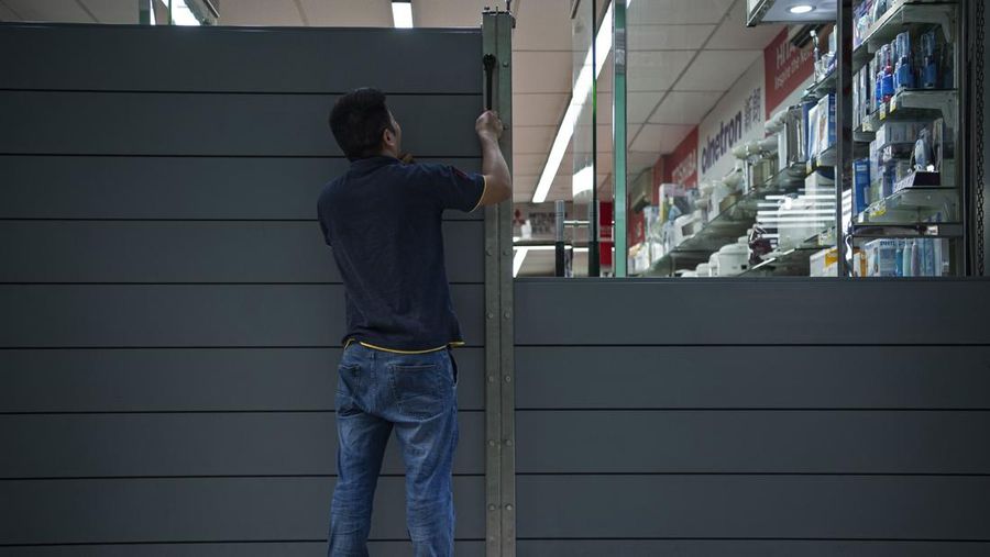 In this photo released by Xinhua News Agency, a worker installs a waterproof gate at a store in Macao, China, Thursday, Aug. 24, 2022. A tropical storm was forecast to make landfall in southern China later Thursday after bringing rain and stiff winds to Hong Kong overnight as it passed to the south of the Asian financial center. (Cheong Kam Ka/Xinhua via AP)