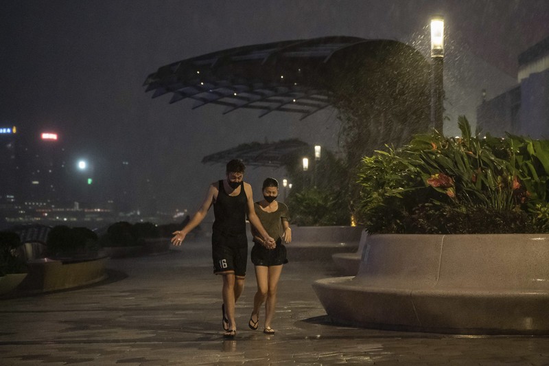 In this photo released by Xinhua News Agency, a worker installs a waterproof gate at a store in Macao, China, Thursday, Aug. 24, 2022. A tropical storm was forecast to make landfall in southern China later Thursday after bringing rain and stiff winds to Hong Kong overnight as it passed to the south of the Asian financial center. (Cheong Kam Ka/Xinhua via AP)