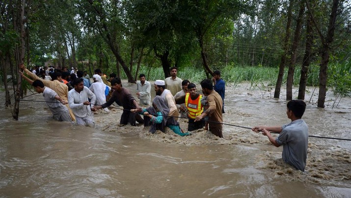 Banjir di Pakistan Orang-orang berjalan melewati banjir saat air banjir masuk ke rumah-rumah dan merusak tanaman yang berdiri di Dagai Mukram Khan, Peshawar, Pakistan, Jumat (26/8/2022). Pemerintah Pakistan mengumumkan keadaan darurat untuk menangani banjir musim hujan yang berdampak terhadap lebih dari empat juta warga yang mengakibatkan 34 orang tewas di negara itu. (Photo by Hussain Ali/Anadolu Agency via Getty Images)