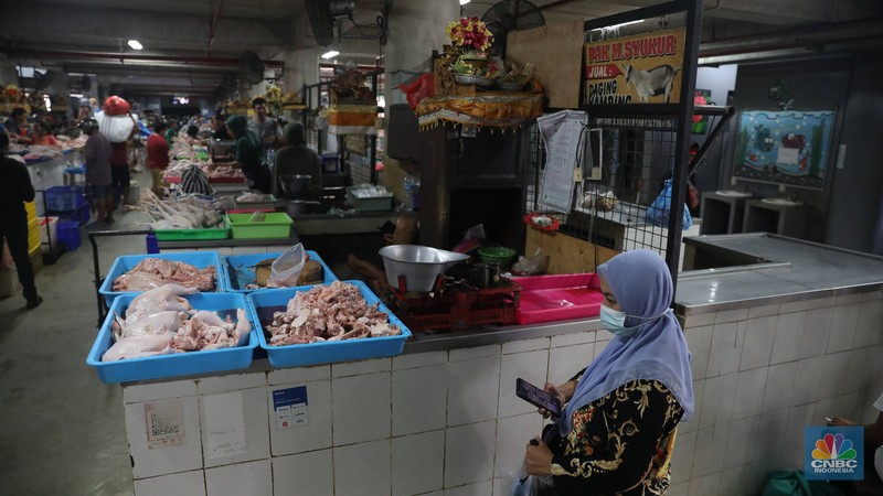 Pembeli membayar belanjaanya dengan menggunakan aplikasi pembayaran digital QRIS (QR Code Indonesian Standard) untuk transaksi dagang di pasar Badung, Denpasar, Bali, Selasa, (30/8/2022). (CNBC Indonesia/Muhammad Sabki)