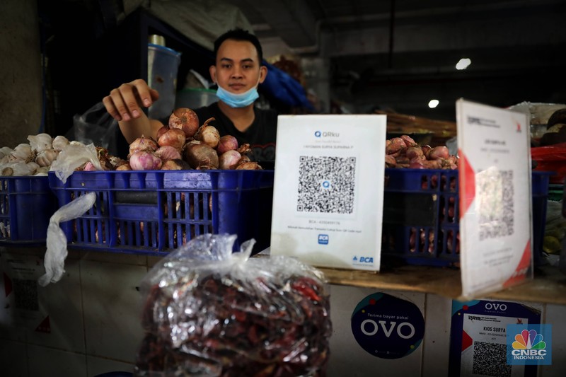 Pembeli membayar belanjaanya dengan menggunakan aplikasi pembayaran digital QRIS (QR Code Indonesian Standard) untuk transaksi dagang di pasar Badung, Denpasar, Bali, Selasa, (30/8/2022). (CNBC Indonesia/Muhammad Sabki)