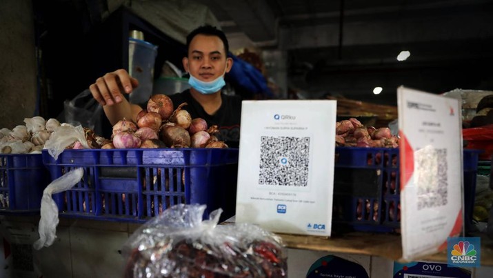 Pembeli membayar belanjaanya dengan menggunakan aplikasi pembayaran digital QRIS (QR Code Indonesian Standard) untuk transaksi dagang di pasar Badung, Denpasar, Bali, Selasa, (30/8/2022). (CNBC Indonesia/Muhammad Sabki)